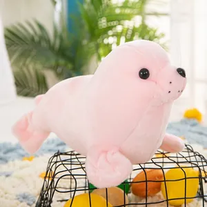 Primer plano lateral de un peluche de foca rosa apoyado en una cesta decorativa negra