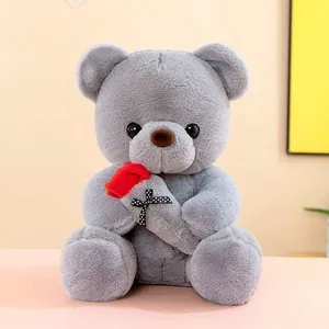 Detailed view of a cute grey plush teddy bear holding a red rose with polka dot ribbon
