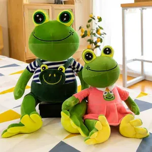 Couple set of smiling green frog plush toys wearing cute overalls and a pink dress