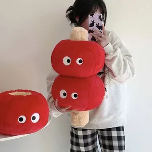 Detail showing a red tanghulu plush pillow with cute cartoon eyes and soft texture