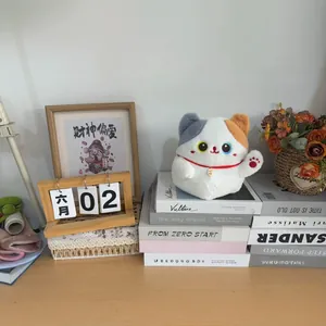Cute tricolor plush lucky cat doll sitting on books in a cozy home office setting