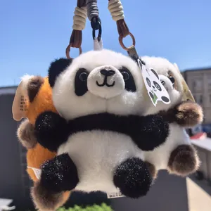 Vista dettagliata di portachiavi in peluche a forma di panda e panda rosso all'aperto
