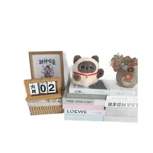 Cute Maneki-neko plush toy as desk decoration on a pile of decorative books
