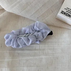 Detail shot of a lavender pleated chiffon hair clip with pearl embellishments