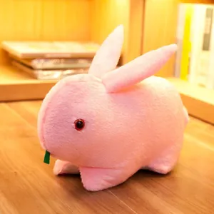 Detailed view of a soft pink rabbit plush toy sitting on a warm wooden desk surface.