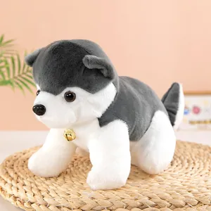 Detail view of a cute husky plush toy dog with a gold bell accessory on a woven mat.