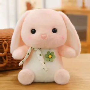 Close-up of a cute pink plush rabbit toy with a green flower and polka dot ribbon.
