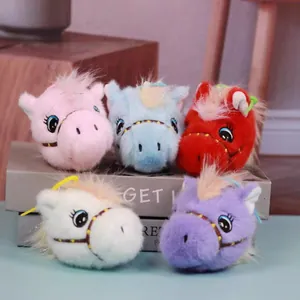 Close-up of five colorful plush pony head keychains on a decorative display box