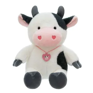 Close-up of a cute plush cow toy with a pink heart necklace on white background