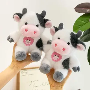 Pair of cute stuffed cow toys being held, showing soft texture and heart details.