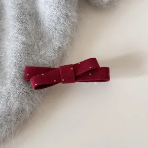 Gros plan d'une barrette à nœud en feutre bordeaux à pois blancs sur un mohair