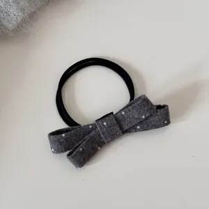 Gros plan d'un chouchou noeud en laine grise à pois blancs avec élastique noir