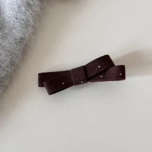 Gros plan d'une pince à cheveux nœud marron à pois blancs avec texture en tissu tricoté