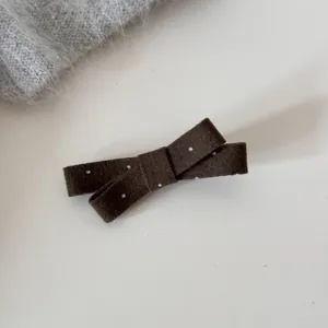 Détail d'une pince à cheveux nœud marron à pois avec une texture mate style français