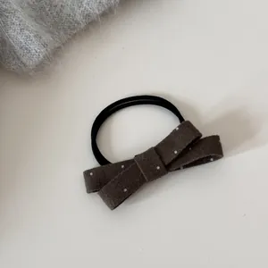 Détail d'un élastique à cheveux avec nœud à pois marron et texture douce au toucher