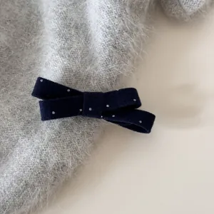 Détail macro d'un accessoire de cheveux nœud à pois bleu marine sur tricot gris doux