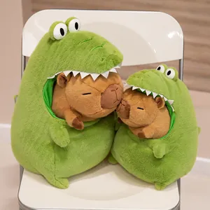 Detailed view of two capybara plush toys in green crocodile costumes on a chair