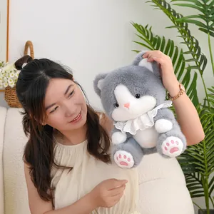 Cute grey and white cat plush doll toy held by a model in a cozy indoor setting