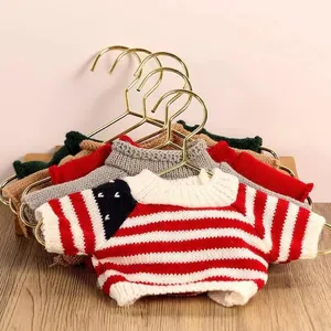 Close-up of miniature knitted sweaters for plush bears on gold hangers