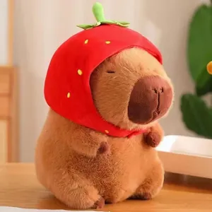 Adorable capybara plush toy with a red strawberry hat detail shown on a wooden table