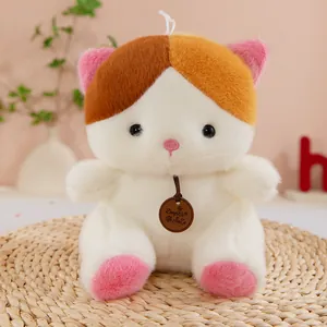 Close-up of a cute sitting plush cat toy with pink ears and calico patches