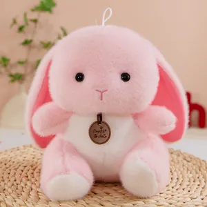 Detailed macro shot of a soft pink plush rabbit toy with a brand tag on a woven mat