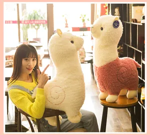 Lifestyle-detail van grote pluizige alpaca knuffels vastgehouden in een gezellig café