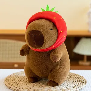 Detailed view of a cute brown capybara plushie wearing a red strawberry-themed hat