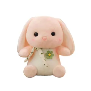 Close-up of cute pink plush bunny with long ears, polka dot bow and green flower.