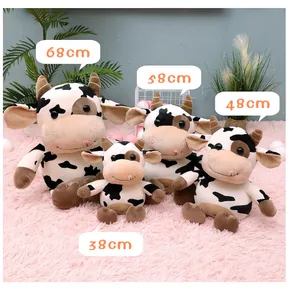 Detailed view of four different sizes of spotted cow plush toys on a pink fluffy rug