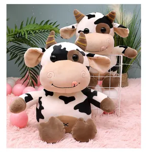 Detail view of two cute black and white spotted cow plush toys on a soft pink rug