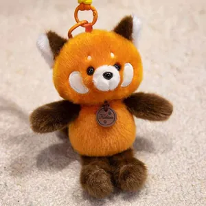 Detailed view of a cute orange red panda plush keychain with soft furry texture and a clip.