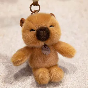 Close-up of a cute brown plush hamster keychain with a soft fuzzy texture and small tag.