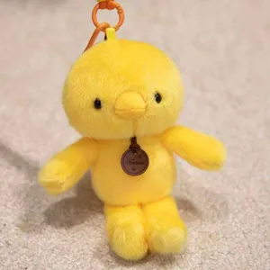Detail view of a cute yellow plush chick keychain with orange clip and fashion tag