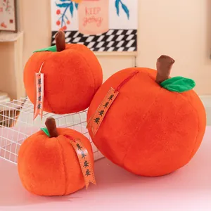 Gros plan de trois peluches en forme de pomme orange avec étiquettes dans un décor.