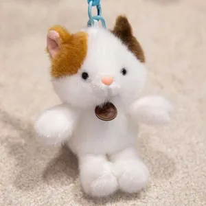 Close-up of a cute calico cat plush keychain with a soft white and brown fur texture