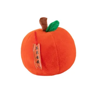 Détail d'une peluche pomme rouge avec feuille verte et étiquette festive traditionnelle.