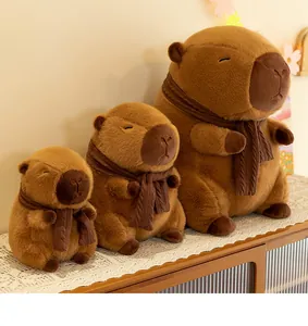 Three sizes of cute capybara plush toys with scarves displayed on a wooden cabinet