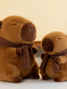 Close-up detail of two cute brown capybara plush toys wearing brown knitted scarves.