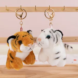 Detalle de lindos llaveros de peluche de tigre y tigre blanco en soporte de madera