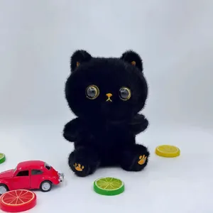 Close-up of a cute fluffy black cat plush toy with large golden eyes on a desk