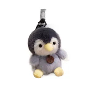 Close-up of a cute gray plush penguin pendant with soft fur and a small leather tag detail