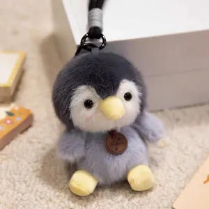 Close-up view of a cute fluffy grey penguin plush keychain with a fashion tag pendant
