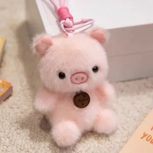 Close-up of a soft pink plush pig keychain with a decorative brown "Fashion" tag.