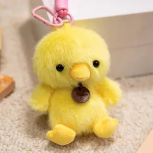 Close-up detail of a soft yellow fuzzy chick plush animal keychain with a pink carabiner clip