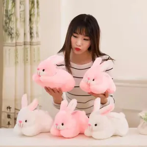 Detail of cute pink and white plush rabbit toys held by a model in a cozy setting