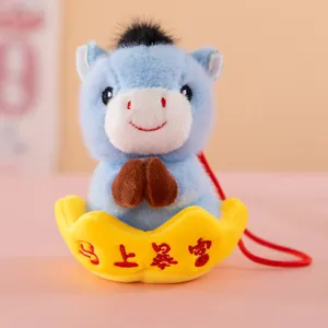 Detail shot of blue plush horse mascot in a yellow gold ingot with red hanging cord