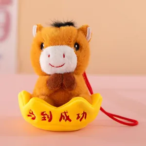 Close-up detail of plush horse mascot keychain sitting in a yellow gold ingot for luck