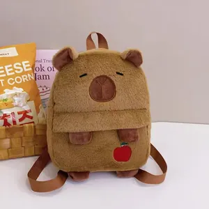 Close-up detail of a cute brown plush capybara backpack with small apple embroidery