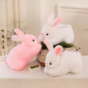 Close-up of three cute white and pink realistic plush rabbit toys in a cozy setting
